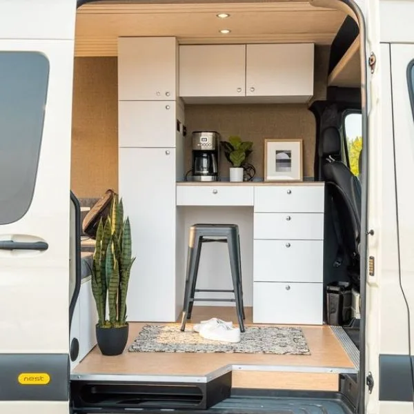 An office space set up inside of a van with a stool and cabinets