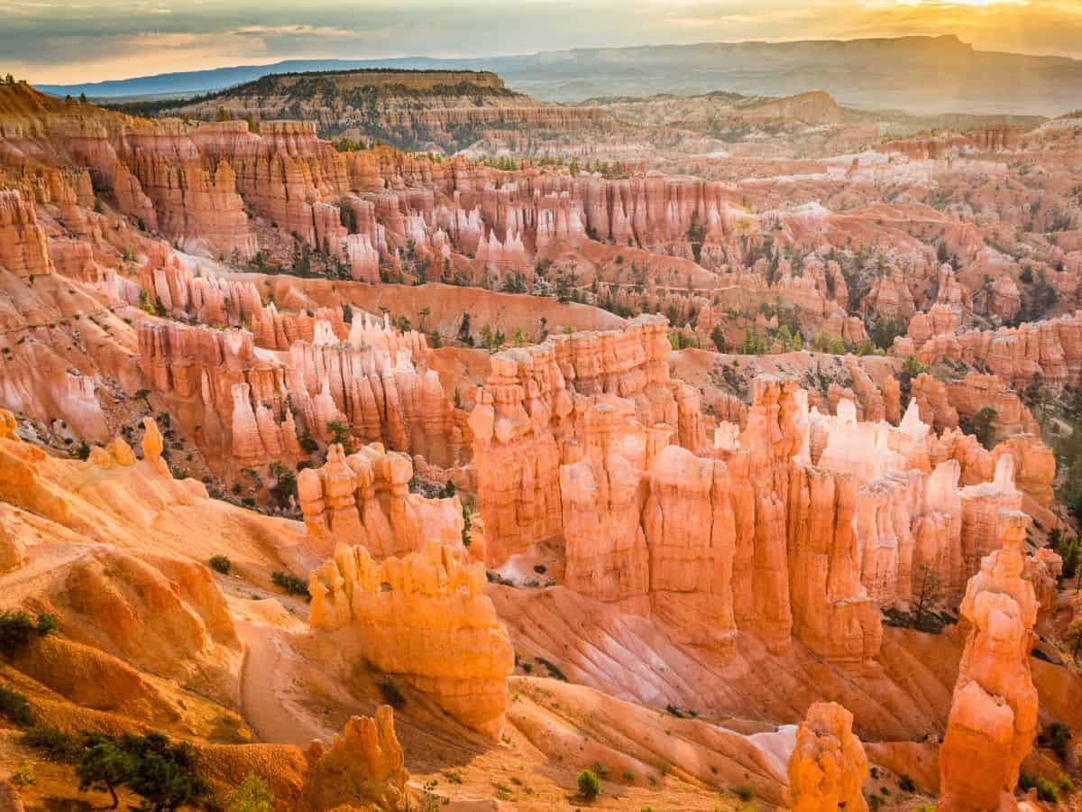 Early morning sun rising over Bryce Amphitheater as seen from Sunrise Point, capturing golden hues across the hoodoos during one day in Bryce Canyon National Park.
