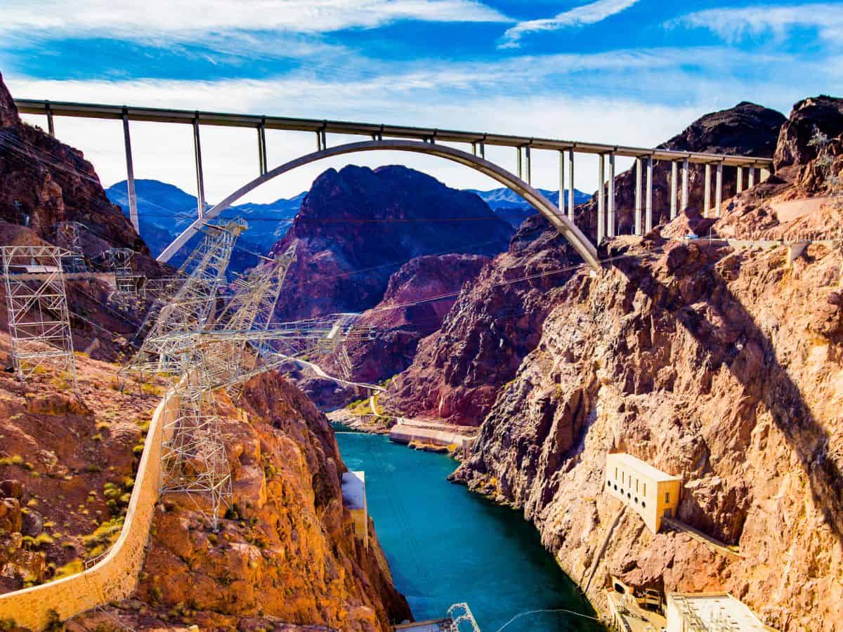 Large arch bridge spanning a deep canyon over the Colorado River near Hoover Dam, a dramatic landmark at the start of a las vegas to zion national park road trip. The sweeping concrete bridge and rugged desert cliffs highlight the engineering marvel and striking Southwest scenery travelers pass on the drive from Las Vegas toward Zion.