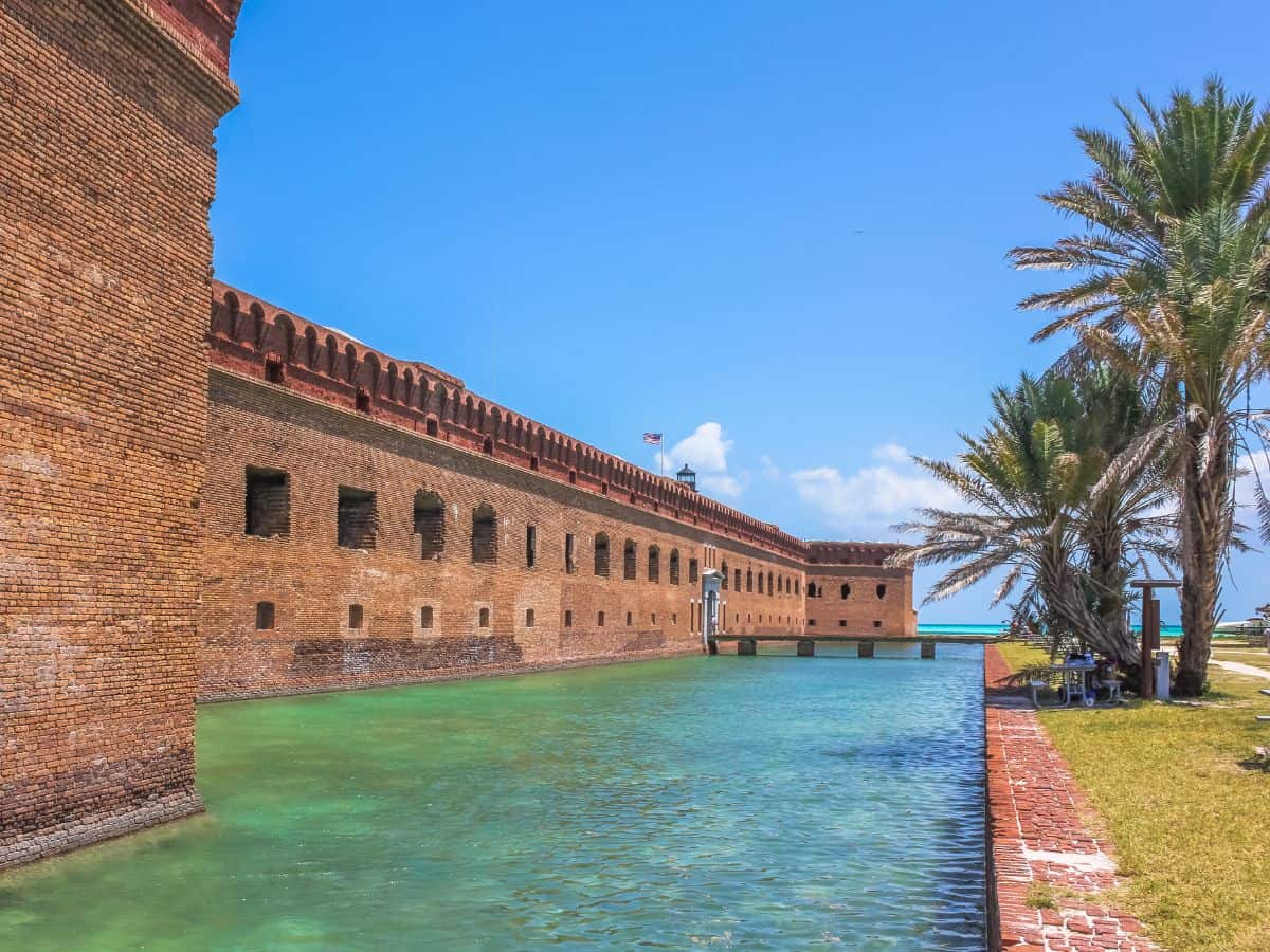A historic red-brick fort surrounded by turquoise water and palm trees stands under a bright blue sky at Dry Tortugas National Park. Its remote island setting and sunny November weather make it one of the best national parks to visit in November for history, snorkeling, and tropical seclusion.