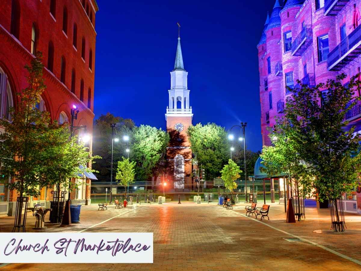 Evening view of Church Street Marketplace in Burlington, Vermont, with colorful brick buildings, glowing streetlights, and the iconic white-steepled church tower, a lively stop on a 7 day New England road trip itinerary.
