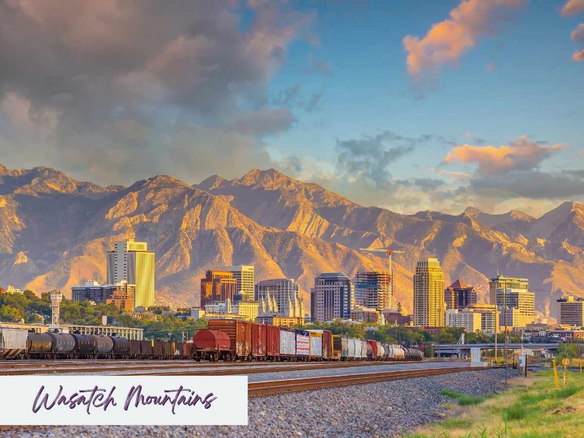 weekend in Salt Lake City itinerary Downtown Salt Lake City skyline framed by the towering Wasatch Mountains at golden hour, with train cars in the foreground—an iconic view to include on a weekend in Salt Lake City itinerary.