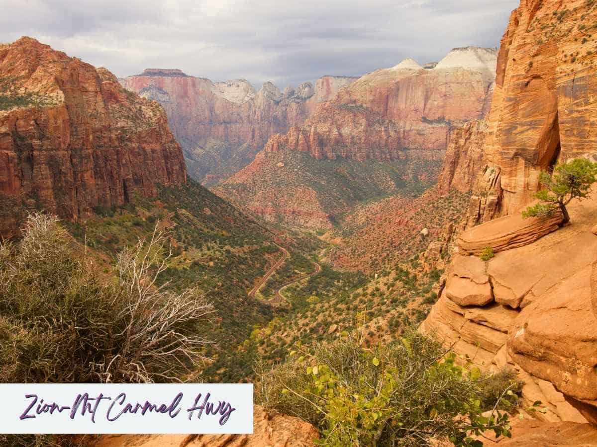 Expansive view of Zion National Park from a high vantage point showing Zion-Mt. Carmel Highway curving through red rock canyons under cloudy skies, illustrating one of the best things to do in Zion National Park besides hiking. Text overlay reads “Zion-Mt Carmel Hwy.”