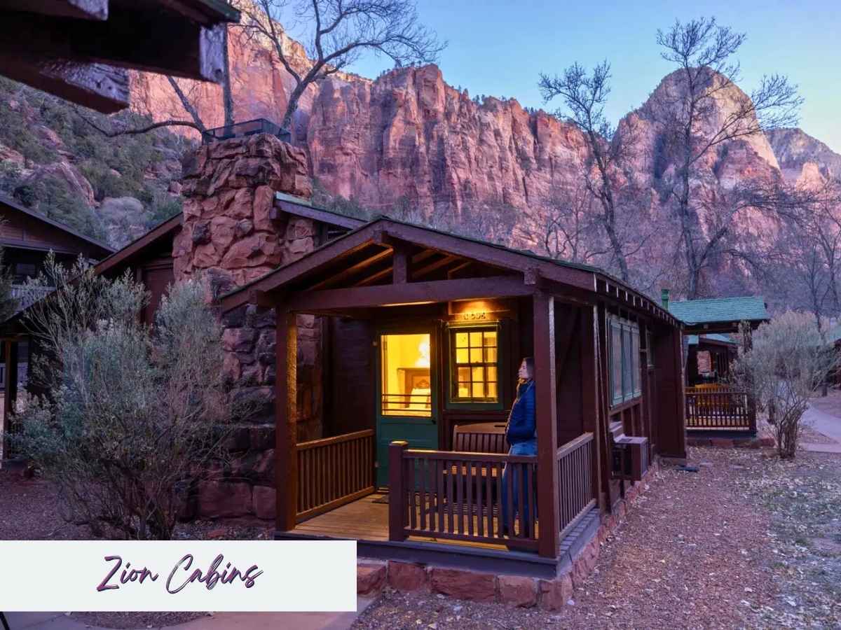 Cozy Zion cabins with wooden porches glow warmly at dusk beneath towering red rock cliffs in Zion National Park. Text on the image reads Zion Cabins, highlighting a charming lodging option to consider when planning a Zion National Park itinerary.